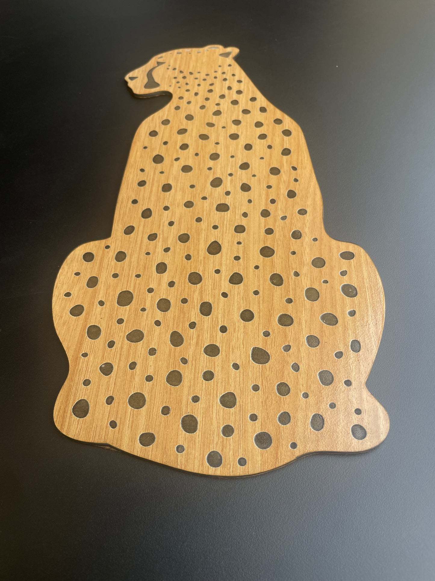 Wooden cutout of a rhinoceros with a spotted pattern on a black background