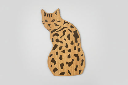 Wooden cat-shaped cutting board with a spotted pattern on a light gray background