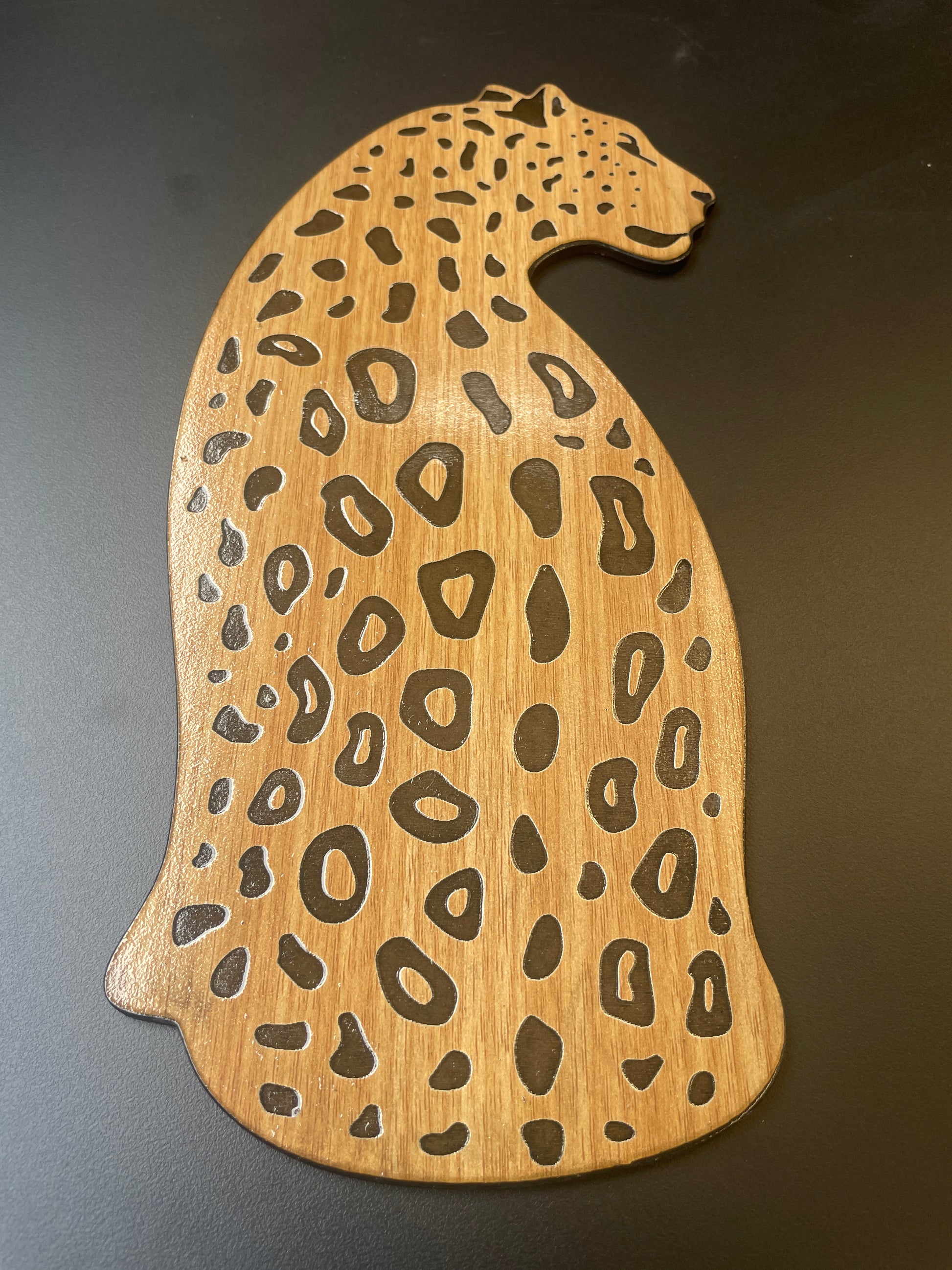 Wooden cutting board shaped like a cheetah with a dark background