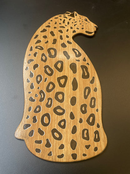 Wooden cutting board shaped like a cheetah with a dark background