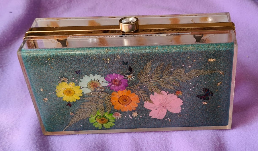 Floral design clutch bag on a purple fabric background